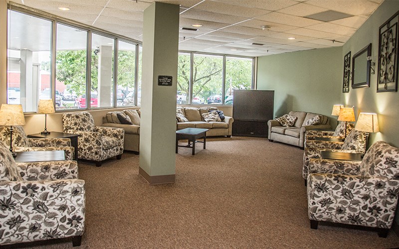 a living room with couches and chairs and large windows
