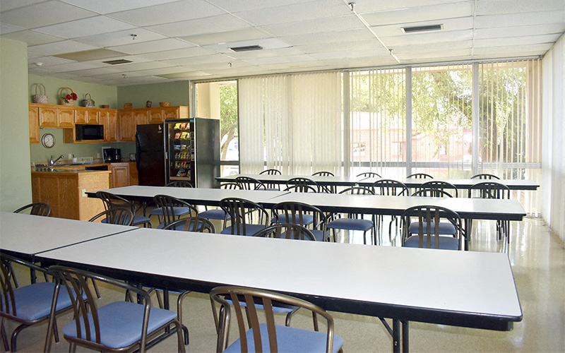 a dining room with tables and chairs and a kitchen