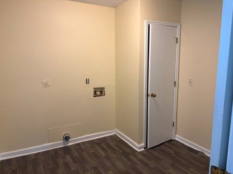 A room with a white door and a brown floor.