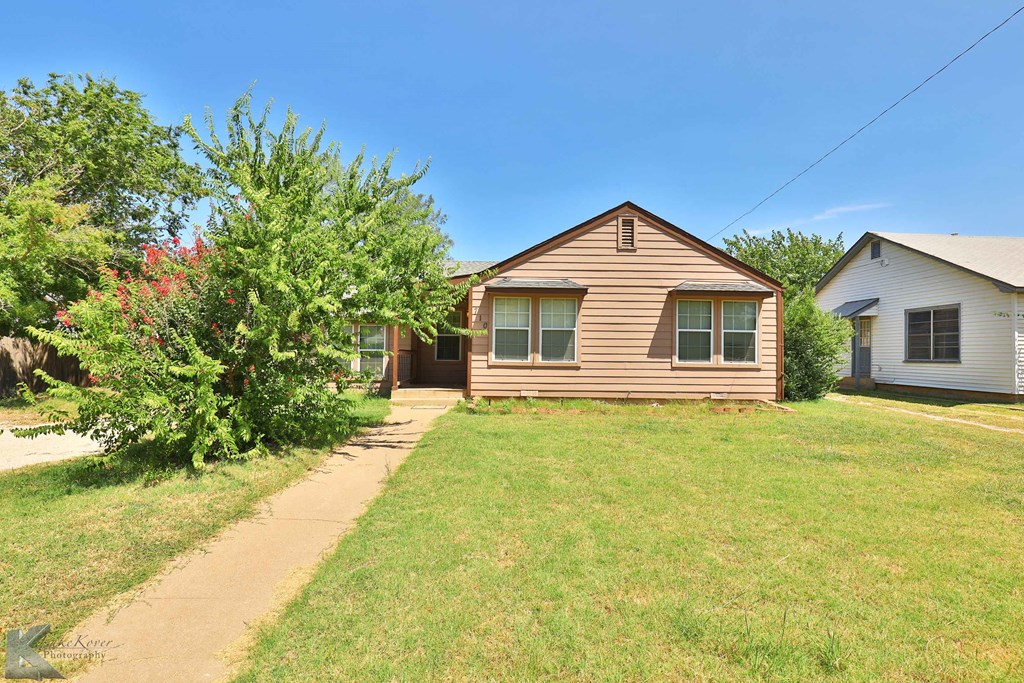 a brown house with a yard and a sidewalk
