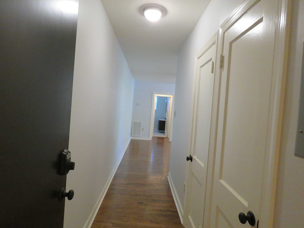 a hallway with white closets and a door to a bathroom
