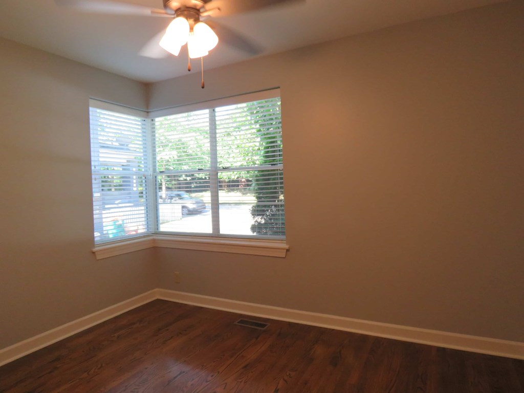 a bedroom with a large window and wood floors