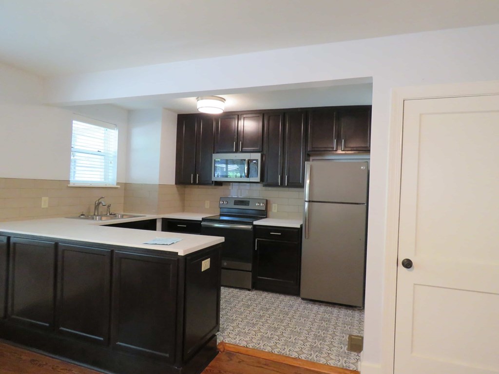 a kitchen with black cabinets and a stainless steel refrigerator