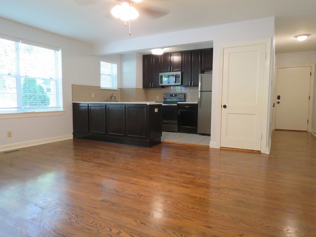 an empty kitchen and living room with wood floors