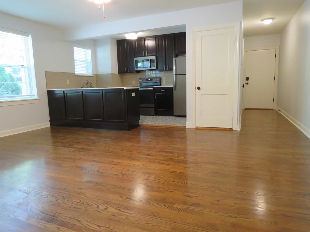 an empty kitchen and living room with wood floors
