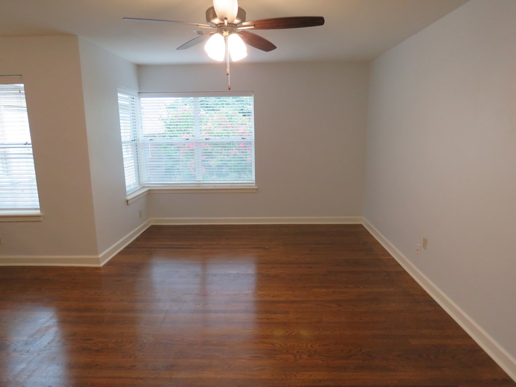 an empty living room with wood floors and a ceiling fan