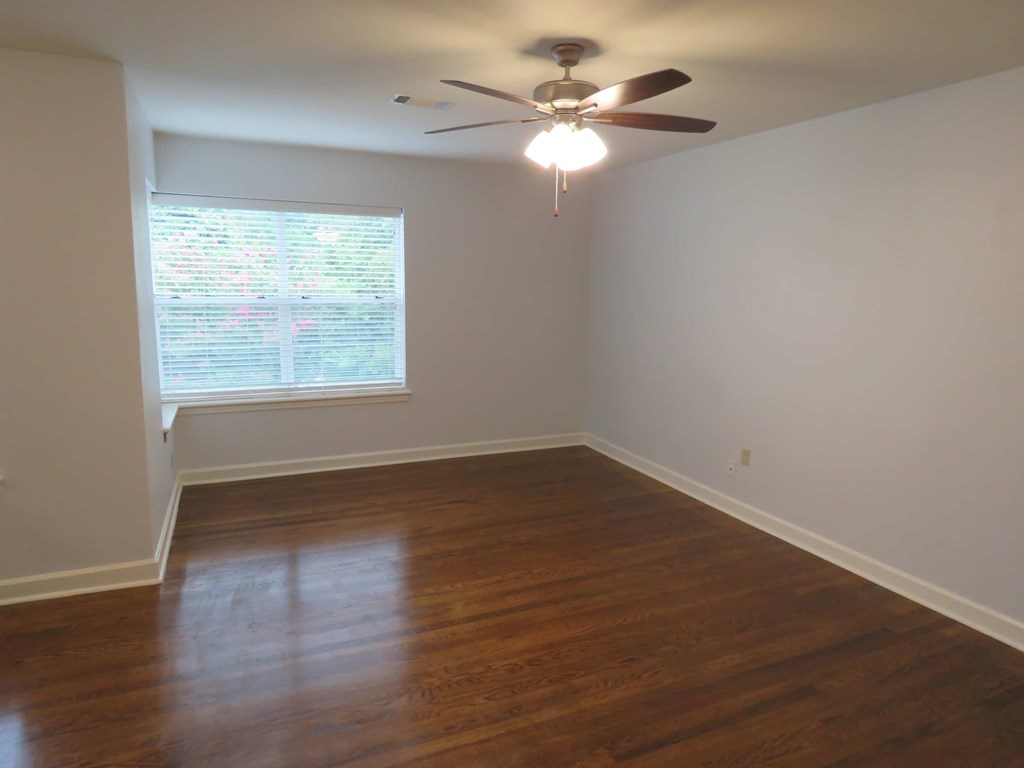 an empty living room with wood floors and a ceiling fan