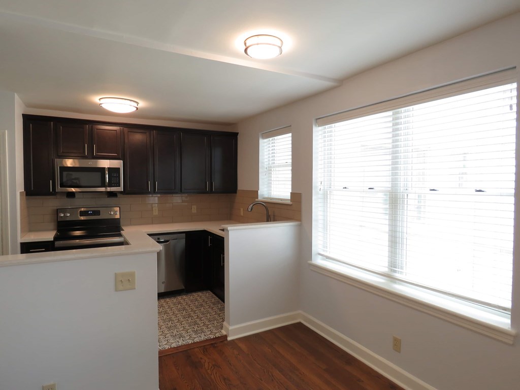 an empty kitchen with black cabinets and a window