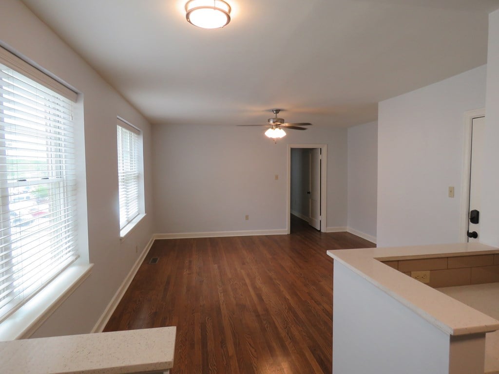 an empty living room with wood floors and a ceiling fan