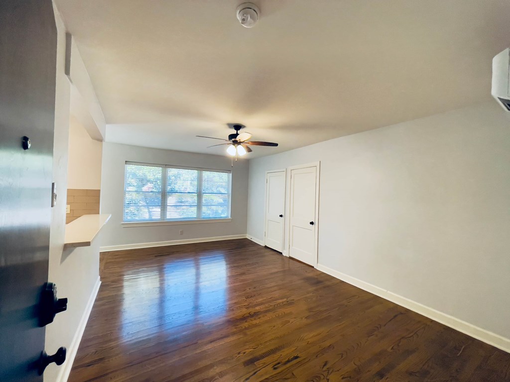 an empty living room with wood floors and a ceiling fan