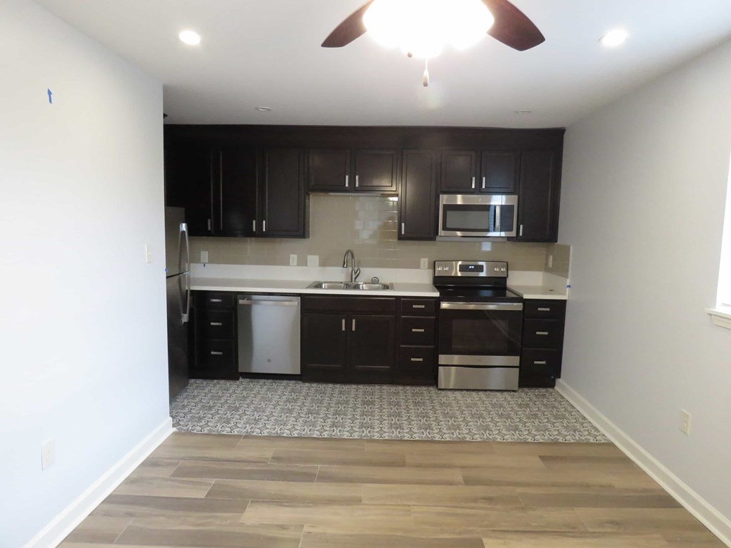 a small kitchen with black cabinets and a wooden floor