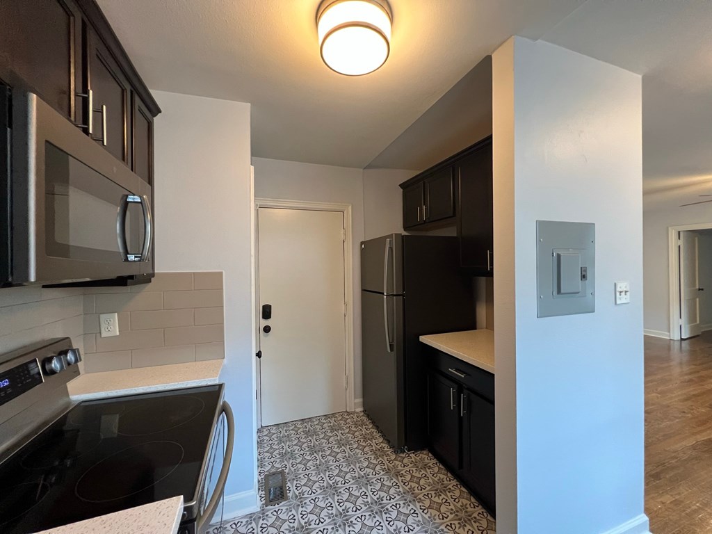 an empty kitchen with black appliances and stainless steel refrigerator