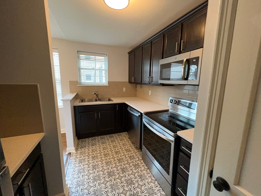a kitchen with black cabinets and a black and white tile floor