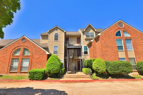 A large brick house with a red door and a balcony.
