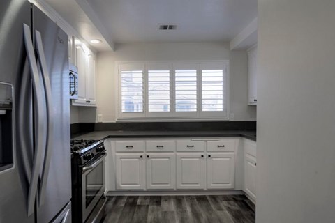 A kitchen with white cabinets and a black countertop.