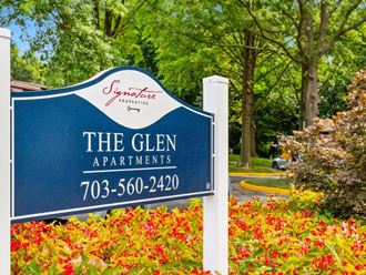 a blue sign with the glen apartments in front of red flowers