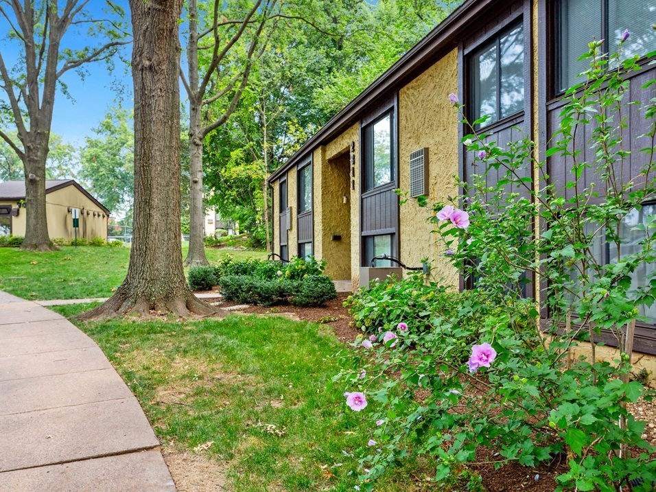 a side view of a house with flowers in the yard