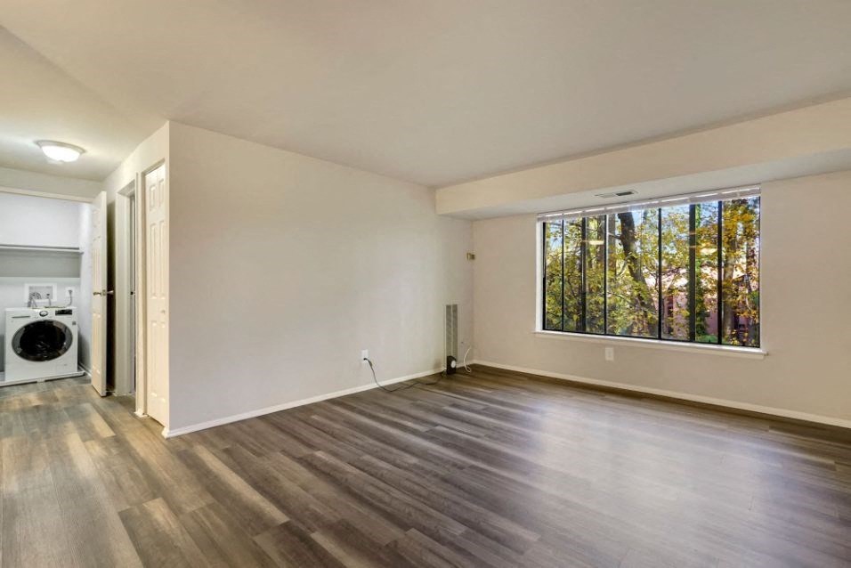 an empty living room with a window and a washing machine