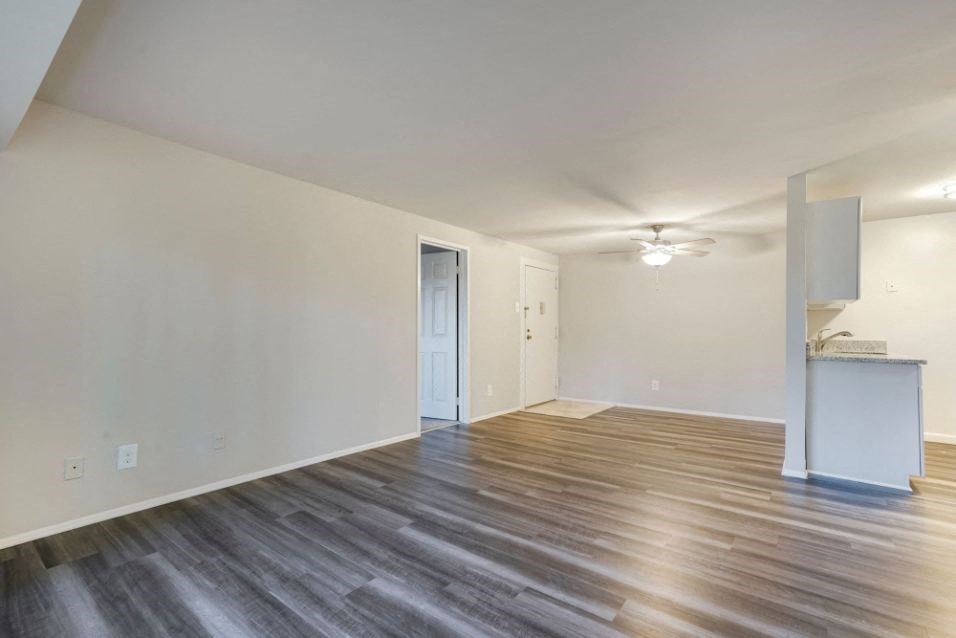 an empty living room with wood flooring and white walls