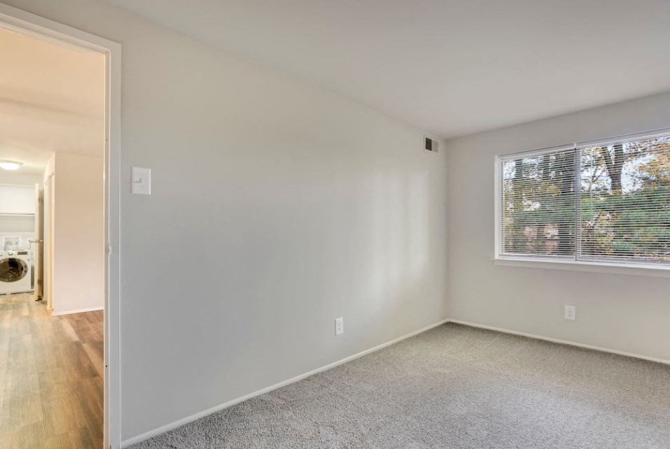 a bedroom with a large window and a carpeted floor