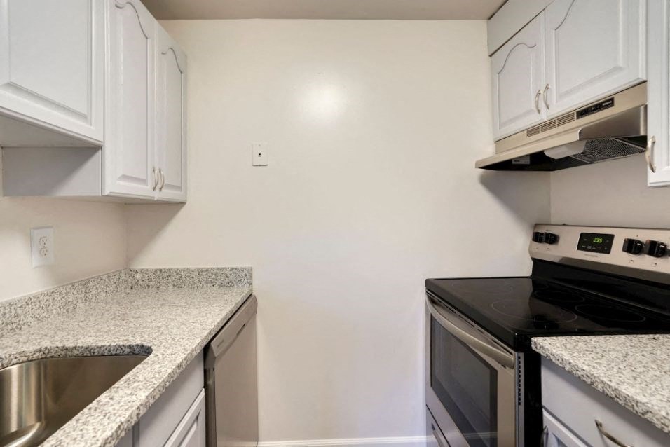 a kitchen with granite counter tops and white cabinets