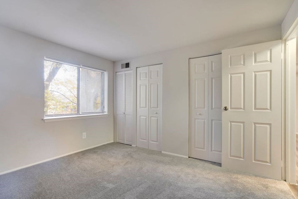 an empty bedroom with two doors and a window