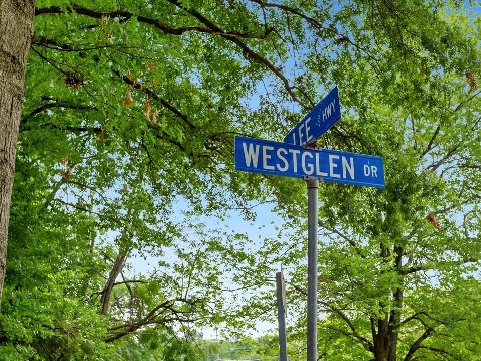 two street signs on a pole in front of trees