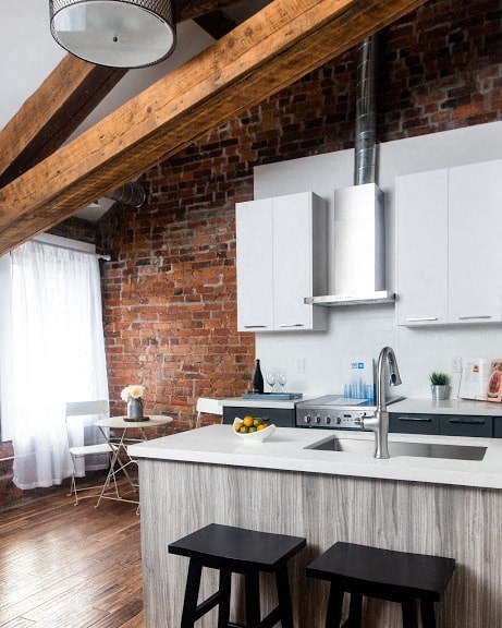 a kitchen with an exposed brick wall and white cabinets