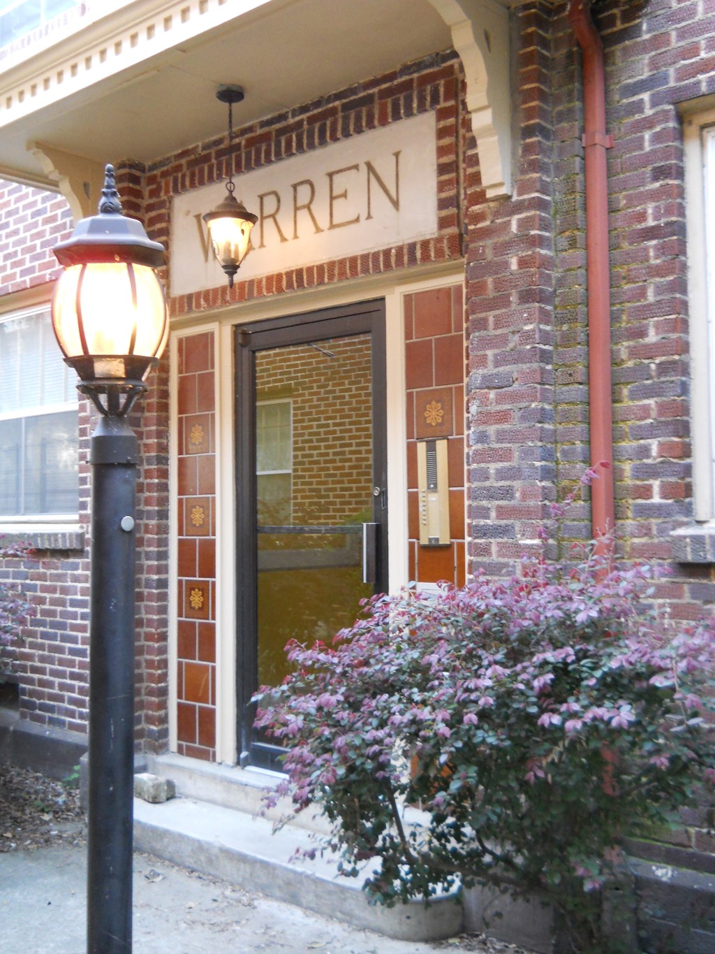 the front door of a brick building with a lamp post