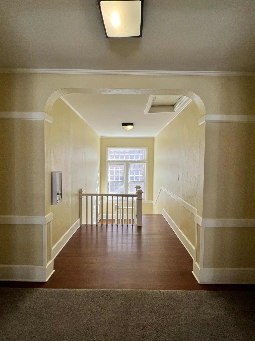 the landing of a house with white walls and a wooden floor