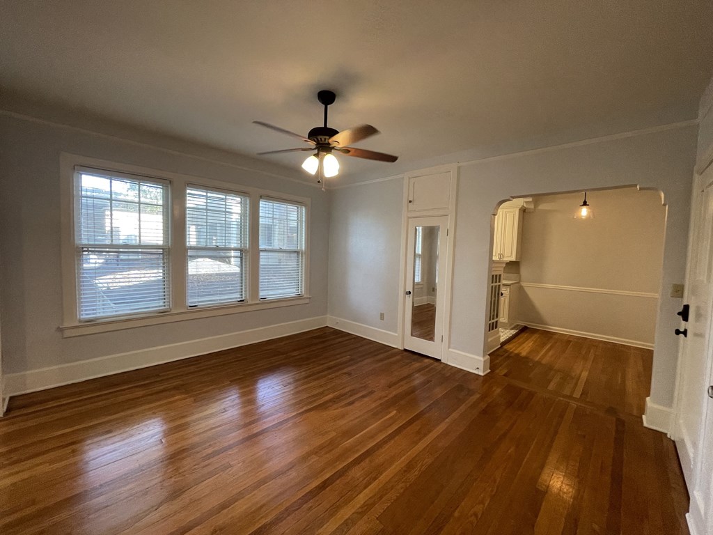 an empty living room with wood floors and a ceiling fan