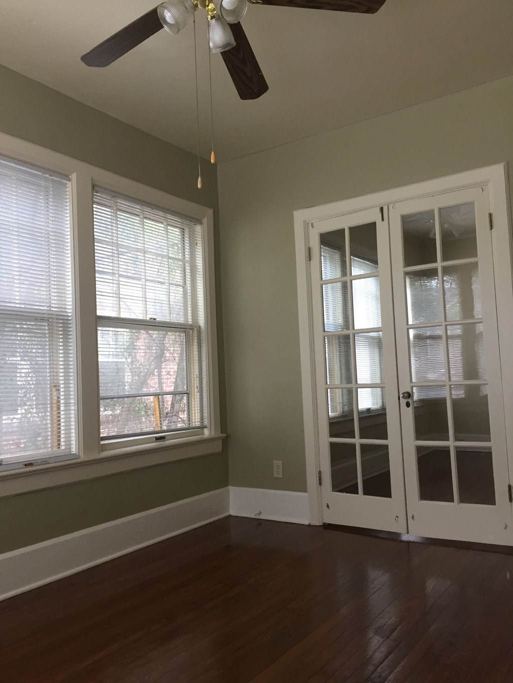 an empty room with windows and a ceiling fan