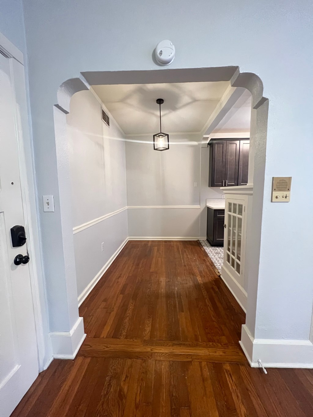 an empty living room with a hard wood floor and an open doorway