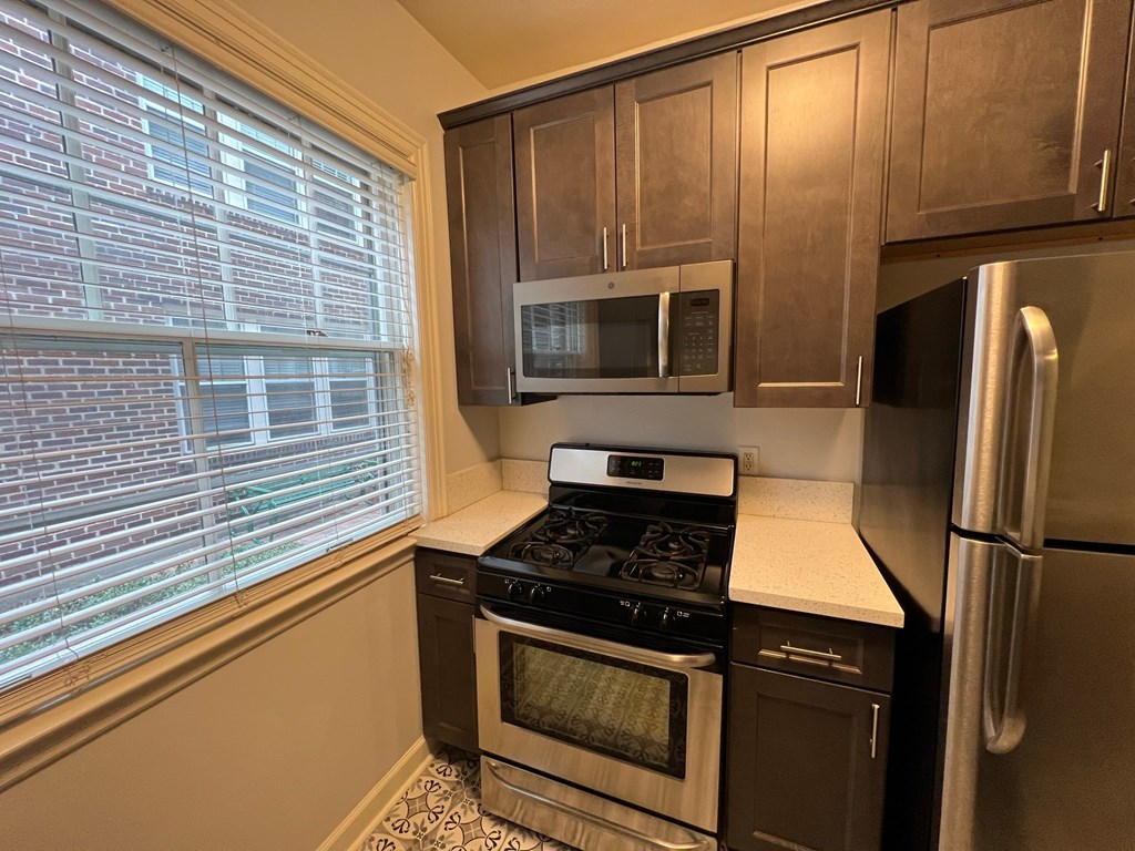 an empty kitchen with a large window and stainless steel appliances