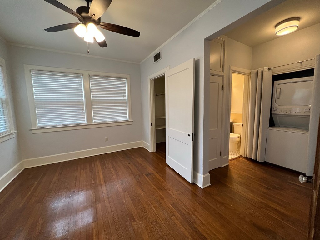 an empty living room with wood floors and a ceiling fan