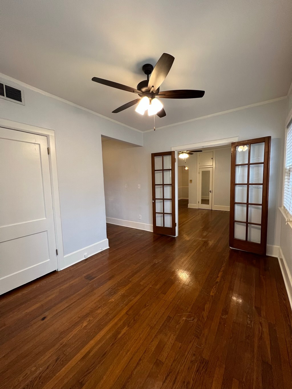 an empty living room with a ceiling fan and wood floors