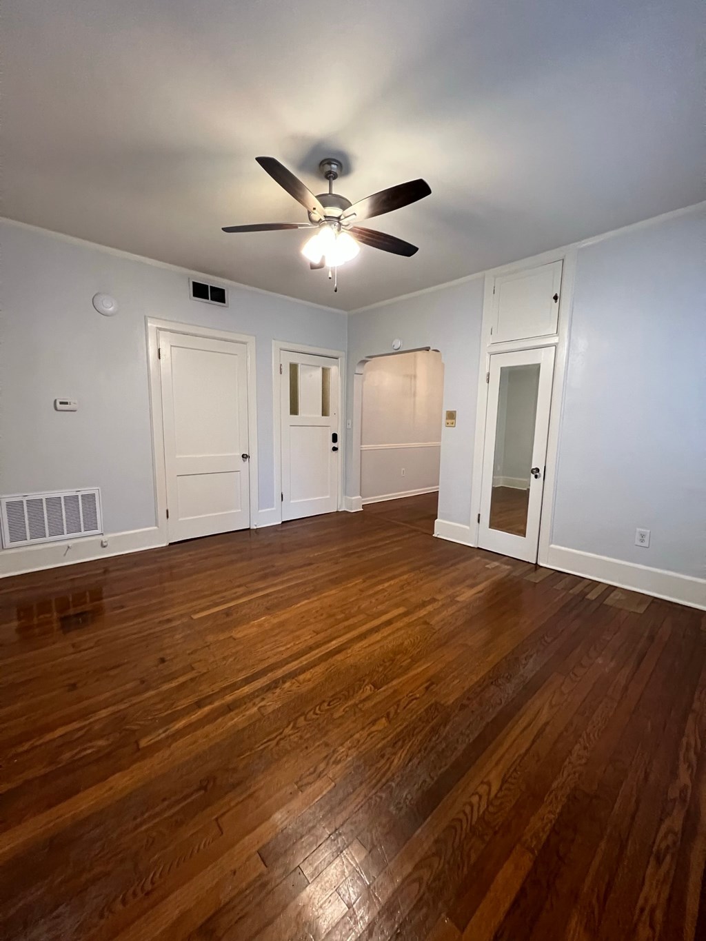 an empty living room with wooden floors and a ceiling fan