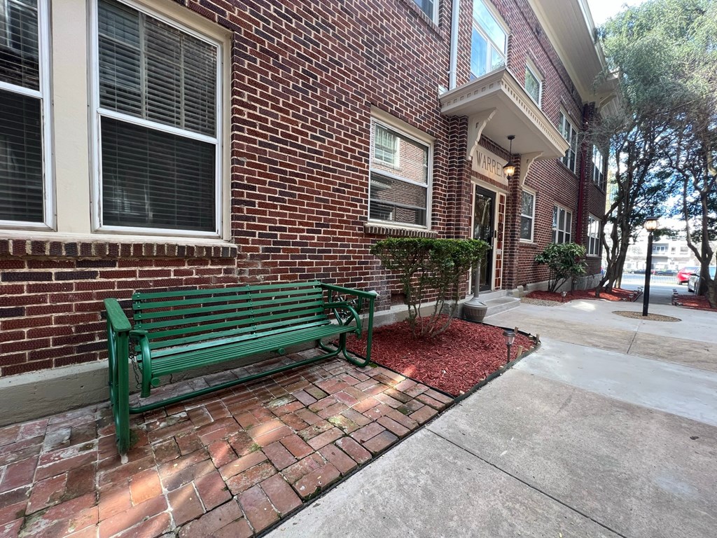 a green park bench in front of a brick building