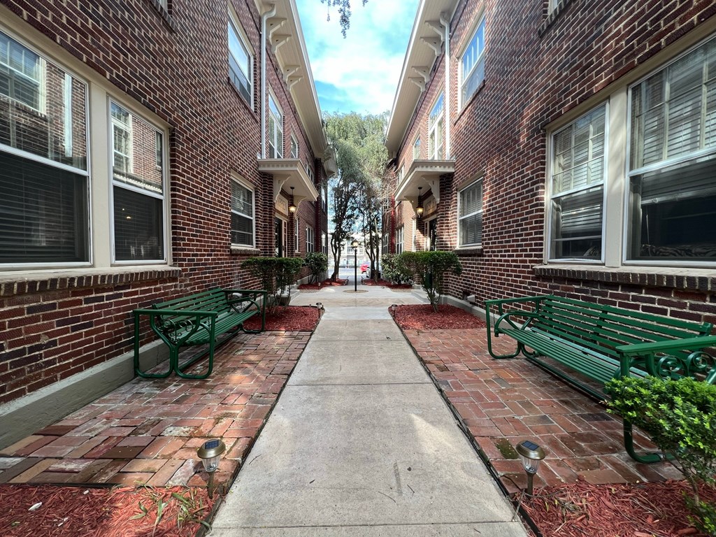 an empty walkway between two brick buildings with benches