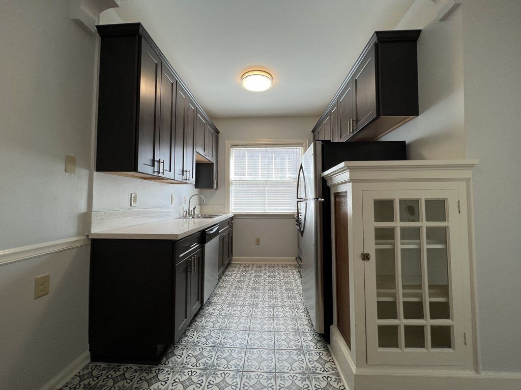 a kitchen with black cabinets and a white counter top and a door