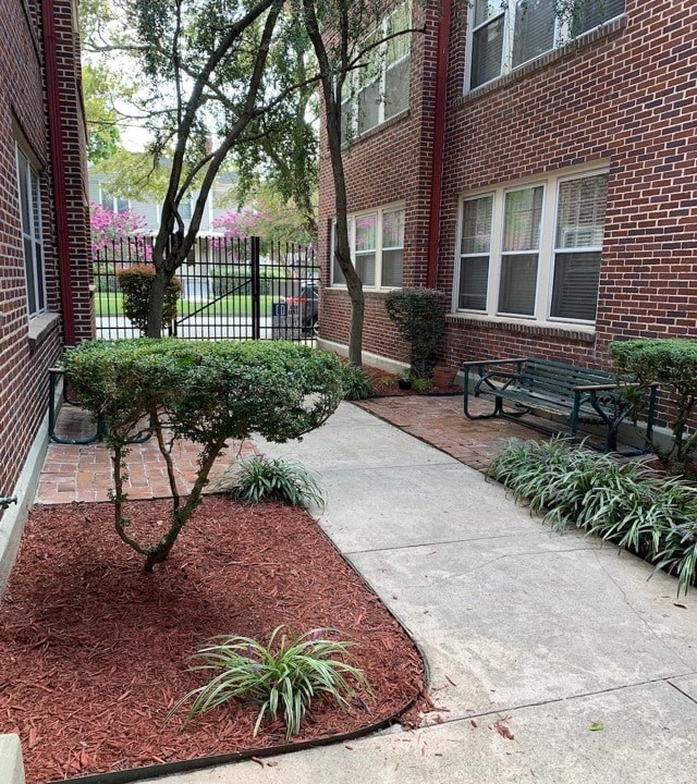 a sidewalk in front of a brick building with a bench