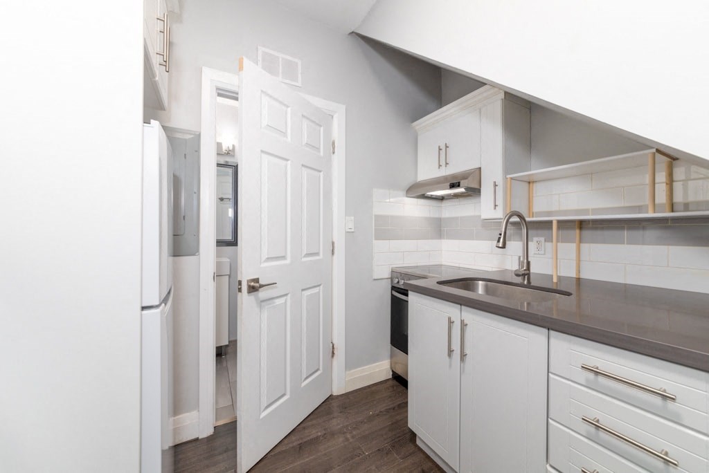 A white kitchen with a refrigerator and a sink.