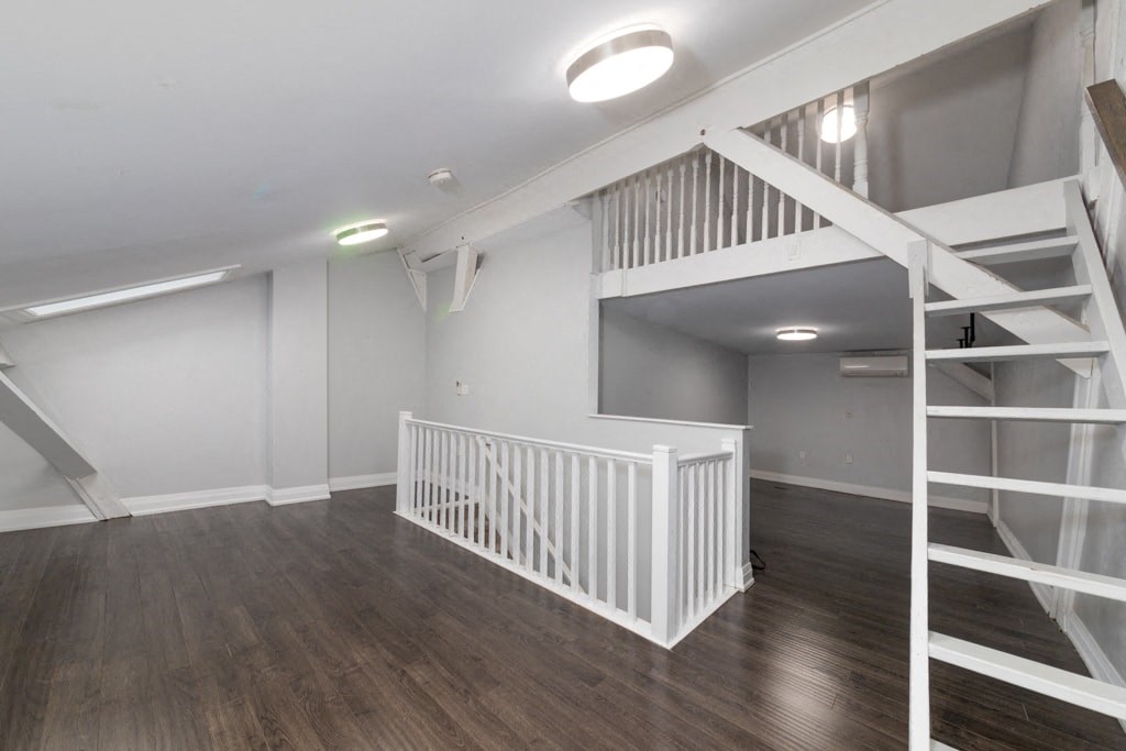 A white staircase with a white railing is in a room with wooden floors.