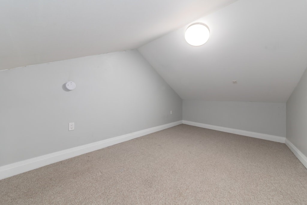 A room with a carpeted floor and a single light source on the ceiling.