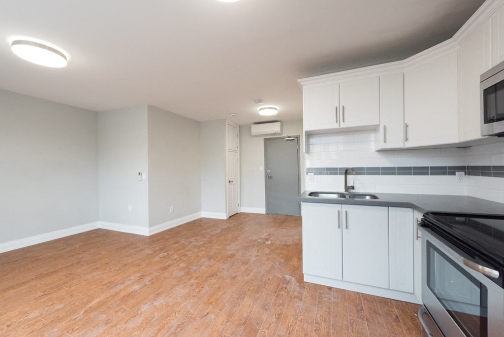 A kitchen with white cabinets and a black countertop.