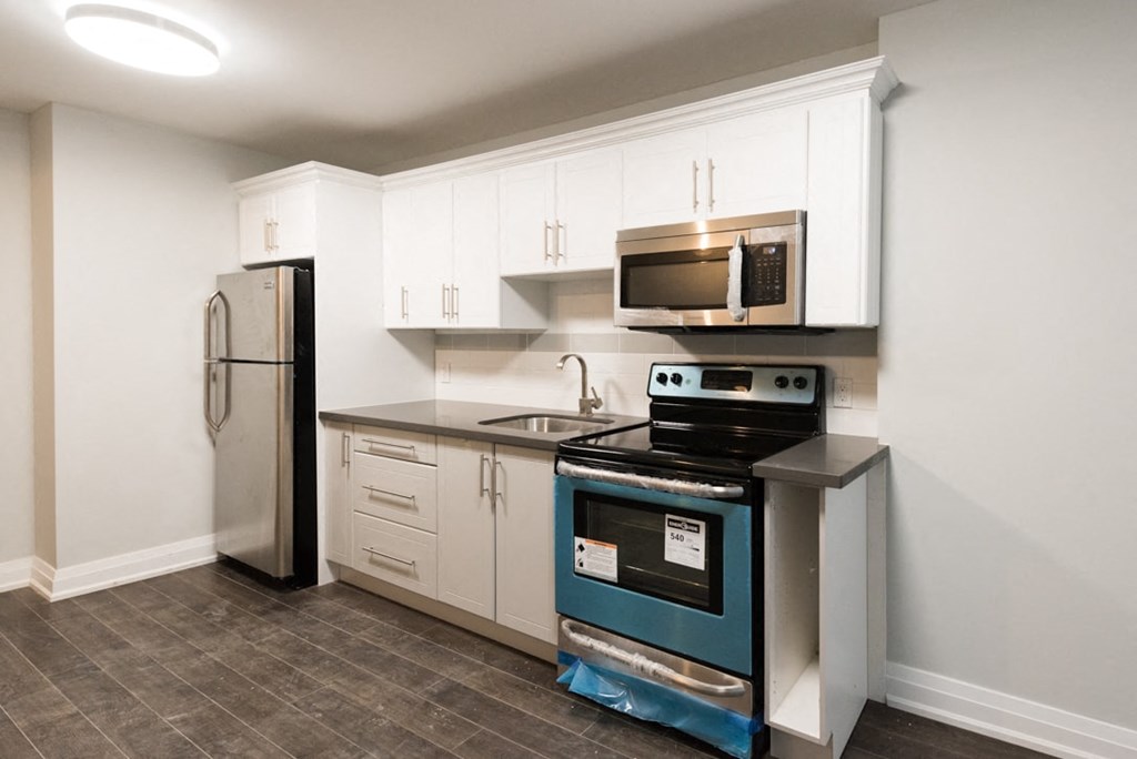 A kitchen with a refrigerator, oven, and microwave.