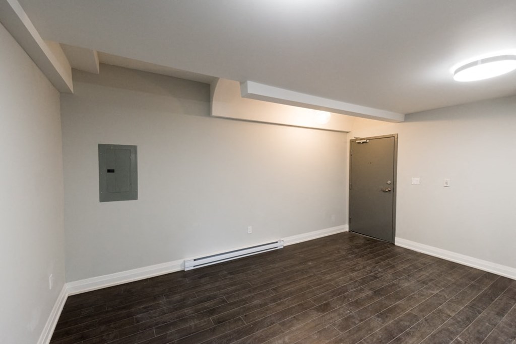 A room with a wooden floor and a grey door.