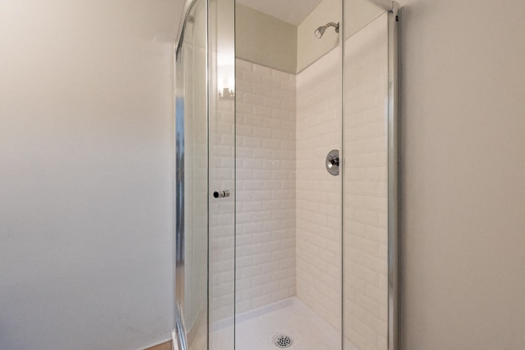 A white tiled shower with a glass door.