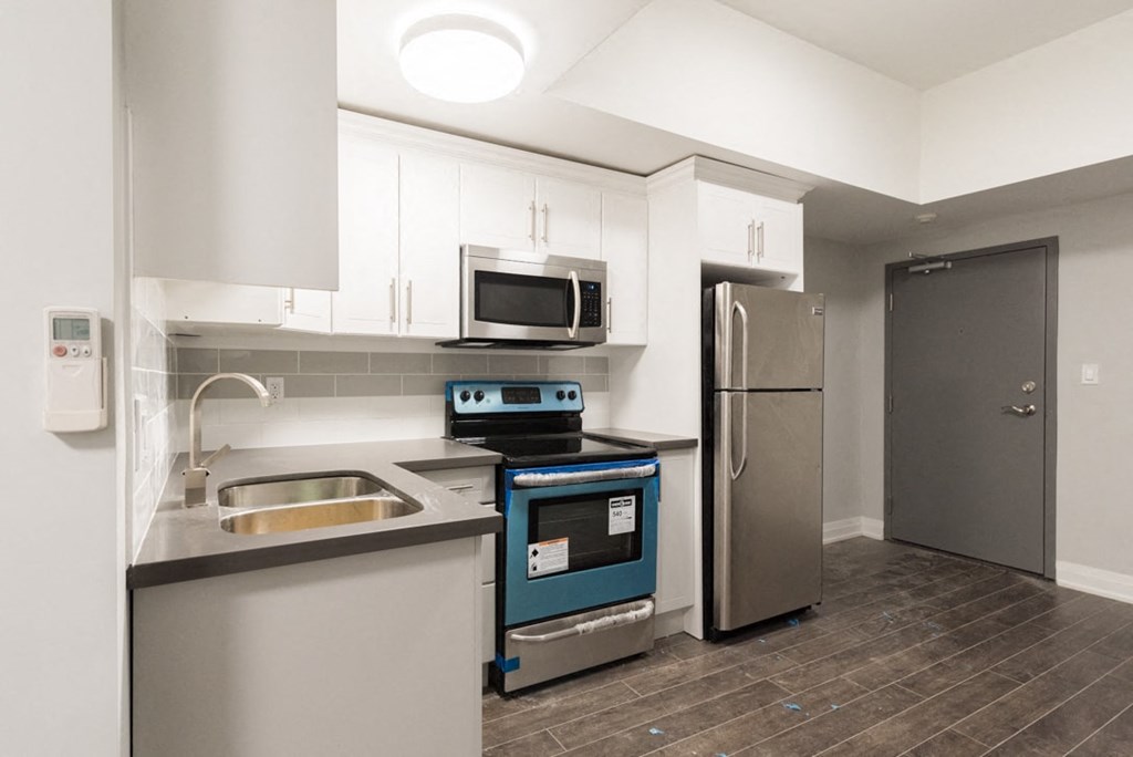 A modern kitchen with a stove, sink, and refrigerator.