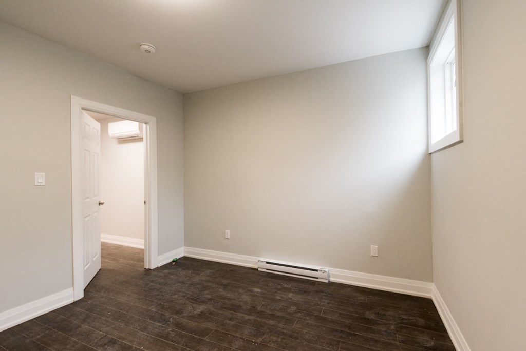 A room with a brown floor and white walls.